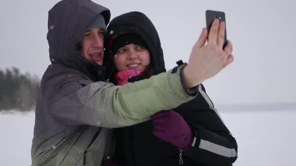 Casal apaixonado posando em uma câmera no inverno, em torno de um lago congelado, 4k — Vídeo de Stock