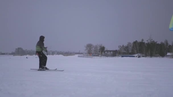 Молодой человек поймал ветер змея, и его нарисовали на снегу, 4k — стоковое видео