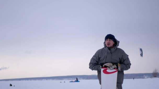 Mladý atraktivní muž stojící s snowboard a povídali, 4k — Stock video