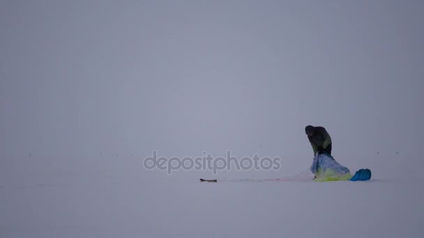 Joven desenreda el paracaídas, arrastrándose sobre la nieve, 4k — Vídeo de stock