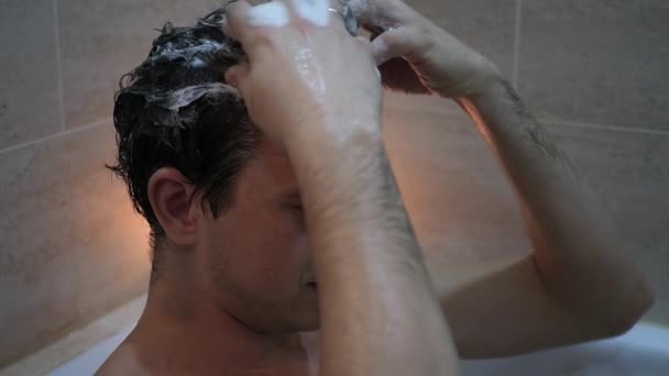 Молодой человек моет волосы шампунем, массирует голову пеной, замедленное движение — стоковое видео