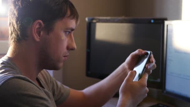 Un hombre joven, conduce un dedo en el teléfono del monitor, al atardecer, 4k — Vídeo de stock