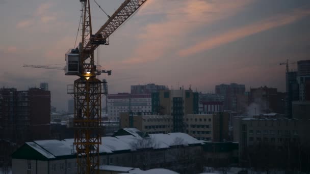 Lavorare nella gru di costruzione in un cantiere al crepuscolo in inverno, 4k — Video Stock