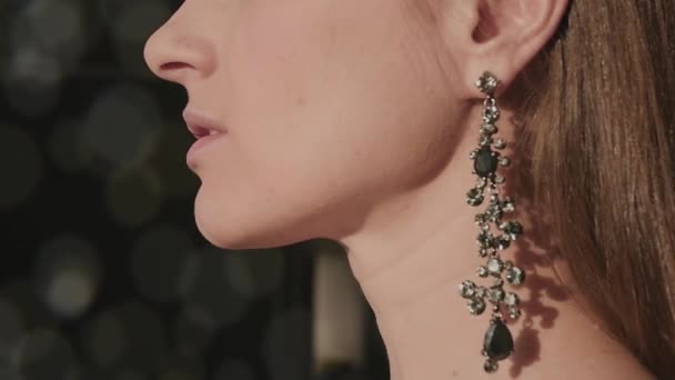 Belle fille dans une belle boucles d'oreilles avec des pierres brillantes dans le profil du soleil avec un fond flou, HD — Video