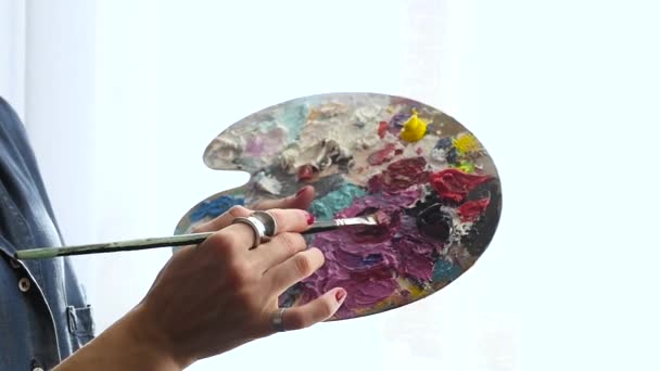 Joven artista mezcla pintura en un color de pincel politrila, cámara lenta — Vídeo de stock