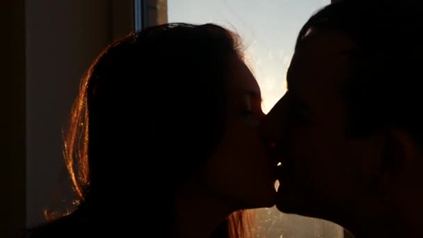 Vlyublonnaya casal beijando ao pôr do sol fora da janela, câmera lenta — Vídeo de Stock