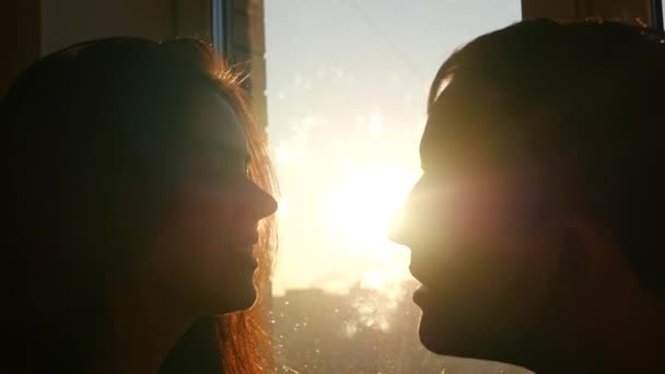 Любящая пара целуется на закате у окна, замедленная съемка — стоковое видео