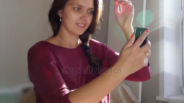 Menina bonita olha para o telefone e endireita o cabelo no reflexo, HD — Vídeo de Stock