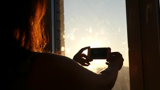 Menina bonita fazendo fotos para fora da janela durante o pôr do sol, HD — Vídeo de Stock