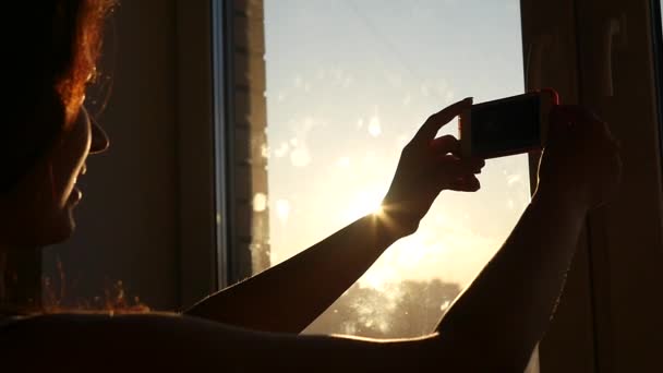 Fare selfie vicino alla finestra al tramonto sul telefono HD — Video Stock