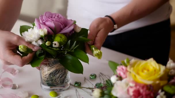 Девушка-флористка собирает красивый букет роз и других цветов в маленькой вазе, 4k — стоковое видео