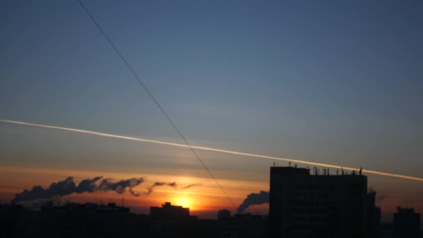 Puesta de sol naranja en la noche sobre un fondo de edificios negros de la ciudad y tuberías con humo, 4k, 3840x2160 — Vídeo de stock