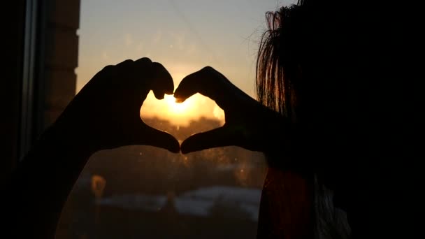 Una declaración de amor con la ayuda de una puesta de sol en la ciudad, y las manos de una joven, doblado en su corazón, HD — Vídeos de Stock