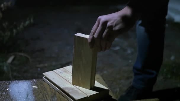 Jonge man hakt brandhout in de straten laat op de avond in het licht van de lamp. Slow-motion. 1920 x 1080 — Stockvideo