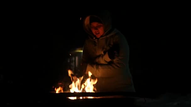 Genç kız gece ve sıcak, kamp ateşi ile ayakta, ellerini ovuşturarak ellerini gürlemesi. 1920 x 1080 — Stok video