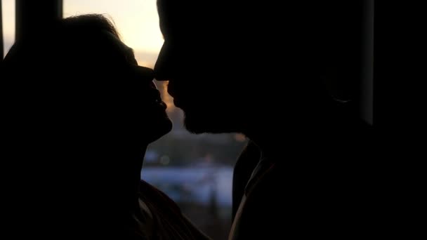 Feliz pareja bonita besándose en el fondo de la ventana a la hermosa puesta de sol de la ciudad. Movimiento lento — Vídeo de stock