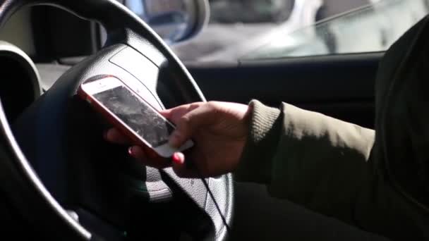 Menina segurando um telefone com uma tela quebrada enquanto sentado ao volante de um carro. 4K 30fps — Vídeo de Stock