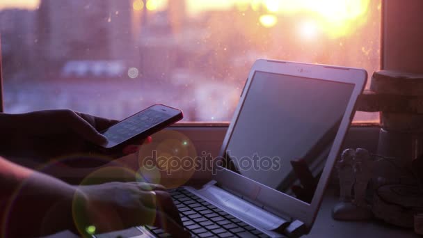 レンズの効果で市夕日の背景に少女の手には携帯電話からキーボードの noutbkua の情報を入力します。3840 x 2160 4 k。 — ストック動画