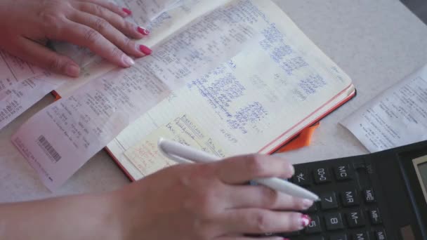 Una giovane ragazza è impegnata nelle finanze, conta su una calcolatrice, riduce le cifre. 4k — Video Stock