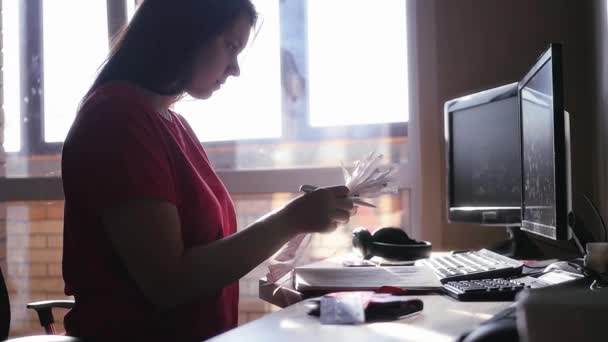 Chica sentada en la mesa sosteniendo en sus manos el papel y leer cuidadosamente. cámara lenta — Vídeo de stock