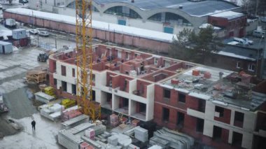 Tuğla yapılmış bir çok Daire bina var. Bir inşaat vinç tuğla ev inşaatçılar oranzhevyh kask Yardım'yükler. 4k