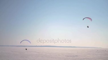 Yerden yükselen iki Yamaçparaşütü mavi gökyüzü kar ile kaplı. Ağır çekim. 1920 x 1080. Hd