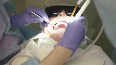 Hasta yalanlar üzerine özel bir koltuk geniş açık ağızlı koruyucu gözlük, diş hekimi diş araçlar yardımıyla inceliyor. 4 k. 3840 x 2160