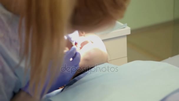 Une fille dentiste examine la cavité buccale de la patiente, travaille avec des outils spéciaux. 4k. 3840x2160 — Video