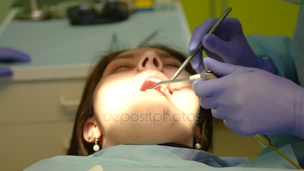 Стоматолог осматривает полость рта молодой девушки, толкает инструмент губами. 4k. 3840x2160 — стоковое видео