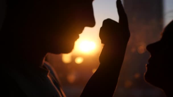 O par jovem no amor, olha um em olhos de outro, contra o pôr-do-sol, com o efeito de uma lente. Ele enfia um dedo na cara. 4k, 3840x2160 — Vídeo de Stock