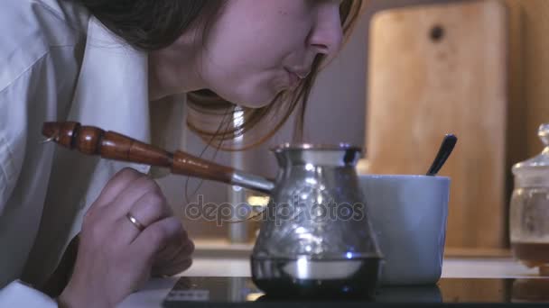 Молодая красивая девушка, дующая на горячий кофе от турок, напиток, чтобы проснуться. 4k, 3840x2160. HD — стоковое видео