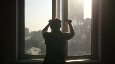 Genç bir kız kanat pencere kapanır, kalemler, evler ve güneş ışığı arka planı döner... Ağır çekim görüntüleri 1080p.