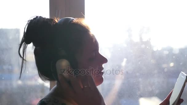 Młoda kobieta w słuchawkach, słuchanie ulubionej muzyki w domu. Ona szuka do telefonu, śpiew i taniec z piosenką. slowmotion. 1920 x 1080 — Wideo stockowe
