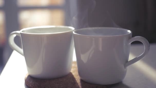 Two beautiful white cups stand on a stoop in the rays of the sun, slow pairs are spinning in the light. slowmotion. 1920x1080 — Stock Video