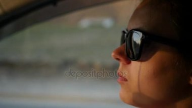 Güneş gözlüklü bir kız bir araba kullanıyor. Ağır çekim. HD, 1920 x 1080.