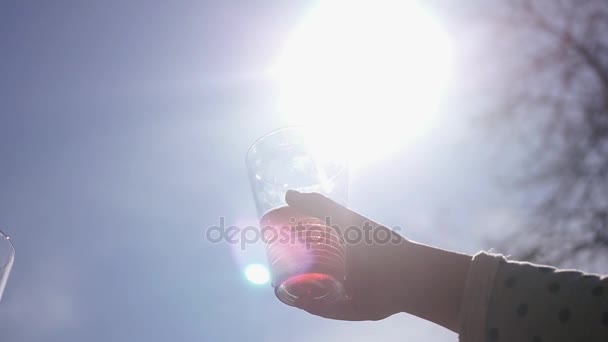 Клінк окуляри з напоями на тлі блакитного неба і яскравого сонця з ефектом лінзи. HD, 1920x1080 . — стокове відео