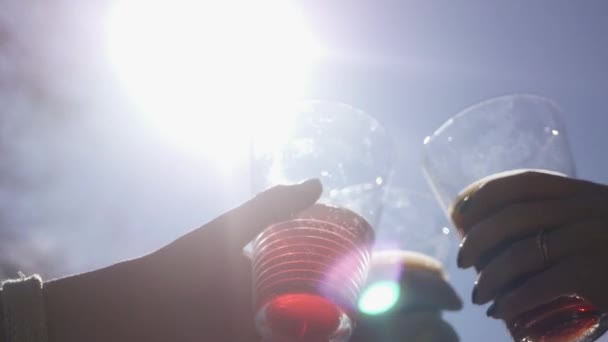 Mensen worden door glas glazen met gekleurde drankjes tegen de blauwe lucht en de felle zon worden gecontroleerd. 4k, 3840 x 2160. HD — Stockvideo