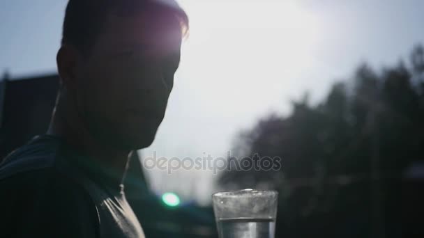Giovanotto con un bicchiere d'acqua pulita contro il cielo e il sole. HD, 1920x1080 . — Video Stock