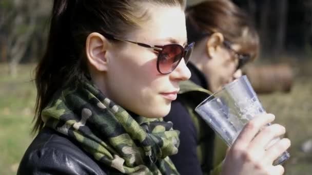 Krásná dívka sedící v profilu pití z skleněnou nádobu s velkým potěšením. 4k, 3840 x 2160. HD — Stock video