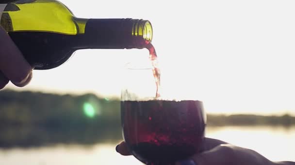 Налейте дорогое вино в бокал на фоне моря с отражениями и эффектом линзы. Slow motion full 1080p — стоковое видео