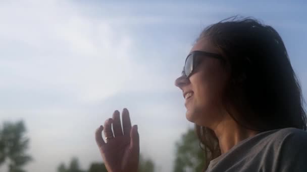 Una ragazza si alza contro il cielo blu con gli occhiali da sole e cerca di toglierli. Al rallentatore. 1920x1080. HD . — Video Stock