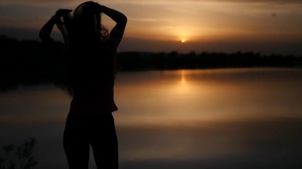 Mladá štíhlá dívka se těší nádherný západ slunce na jezeře, s rukama nataženýma. Zpomalený pohyb. 1920 × 1080 — Stock video