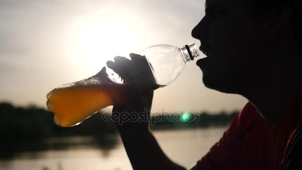 Saciar a sede com uma bebida espumosa de uma garrafa ao pôr do sol com destaques. Fecha. câmara lenta. HD. 1920x1080 — Vídeo de Stock