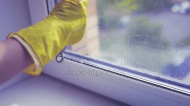 Pencerenin bir sarı lastik eldiven bir kazıyıcı ile temizleyin. Ağır çekim. HD, 1920 x 1080.