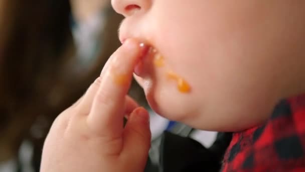 Un niño come con apetito una deliciosa fruta jugosa, se sube los dedos en la boca. Lento movimiento. HD, 1920x1080 . — Vídeo de stock