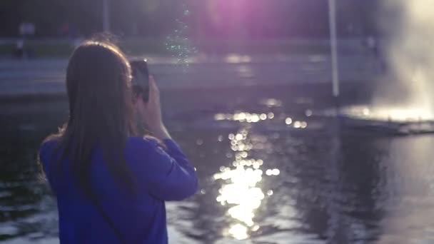 Young beautiful girl takes on the phone a fountain and spray away. SLOW MOTION. HD, 1920x1080. — Stock Video