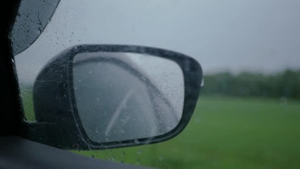 Viaggiare in auto sotto la pioggia, gocce di pioggia sul finestrino laterale e lo specchio dell'auto. SLOW MOTION. HD, 1920x1080 . — Video Stock