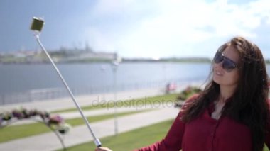 Güzel genç kız resmi selfie sopa defne ve güzel manzaranın arka planı için yapıyor. HD, 1920 x 1080. Ağır çekim