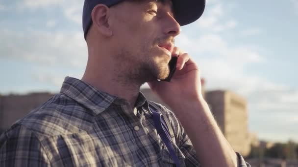 A young man in a cap speaks on the phone and nods his head. HD, 1920x1080. Slow motion — Stock Video