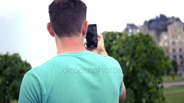 Een jonge man communiceert via de telefoon op een video van communicatie, toont de wijk van de stad. HD, 1920 x 1080. Slow motion — Stockvideo